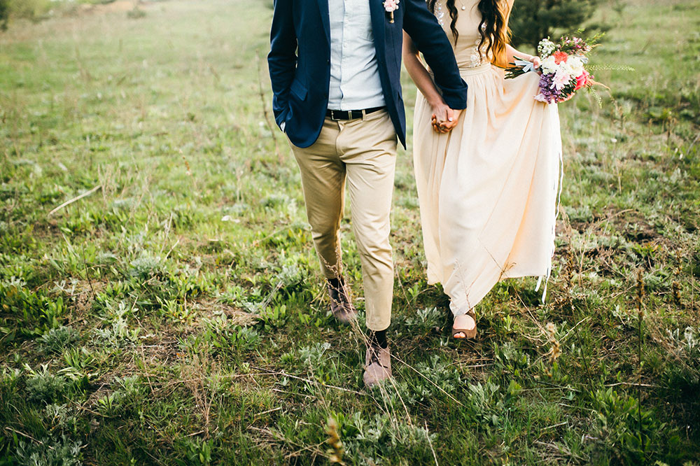 bride and groom running through a field